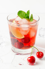 refreshing red cocktail with sparkling water and ice garnished with a lime and cherry