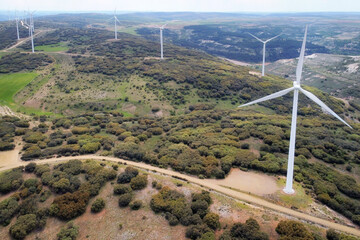 Aerial view of windmills farm for clean energy production on beautiful cloudy sky. Wind power turbines generating clean renewable energy for sustainable development .