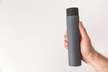 Grey bottle of shampoo or lotion in male hand isolated on white background. Copy space, mock up.