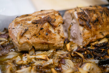 Meat with onions from the oven. The pan with roast pork, knife and tongs are near. Close-up view.