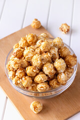 Sweet caramel popcorn in glass bowl. Close up. Light background.