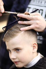 Barber cuts the boy with scissors