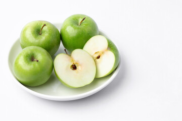 Fresh green apples in a dish on white background