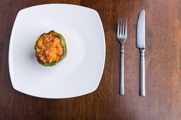 Homemade stuffed green bell pepper served on a wooden table. View from above.