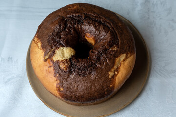 HOMEMADE RUSTIC CAKE, ON THE TABLE HAVING A CUP OF COFFEE IN THE BACKGROUND