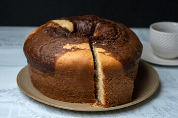 HOMEMADE RUSTIC CAKE, ON THE TABLE HAVING A CUP OF COFFEE IN THE BACKGROUND