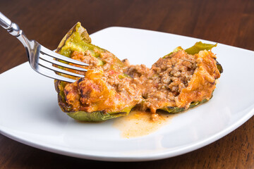 Grabbing the first bite of a stuffed and halved green bell pepper.
