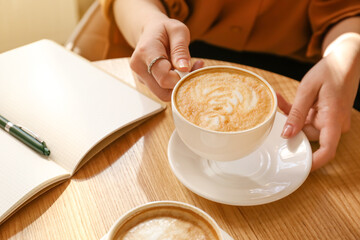 Woman drinking tasty coffee at table in cafe