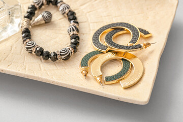 Plate with beautiful jewelry on light background