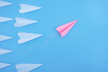 Fototapeta na wymiar Pink paper plane is different from others on a blue background. Think differently, business leader concept.