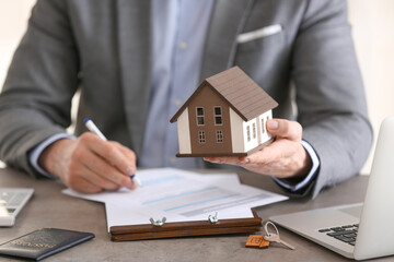 Fototapeta na wymiar Male agent with home insurance form and model of house, closeup