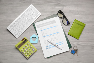 Home insurance form with computer keyboard, key, passport and calculator on table