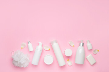Shower gels with bath supplies on color background