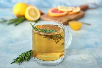 Cup of hot tea with rosemary on color background