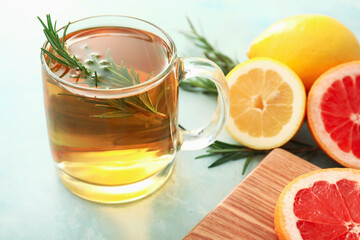 Cup of hot tea with rosemary on color background