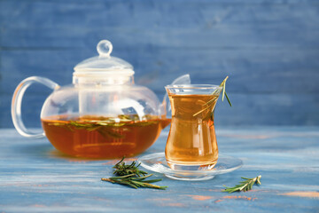 Cup and teapot of hot tea with rosemary on table