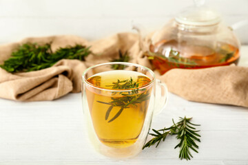 Cup of hot tea with rosemary on table