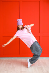 Young female hip-hop dancer against color wall