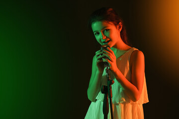 Obraz premium Cute little girl singing against dark background