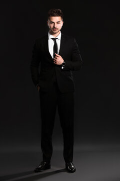 Handsome young man in elegant suit on dark background