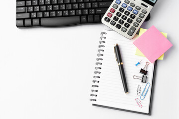Pen, calculator, keyboard, paper clips on notebook  on white background