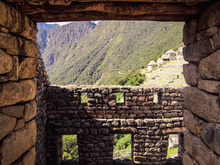 View of a hillside in Machu Picchu, Peru, seen from a window built with stone and wood. Archaeological ruins of the ancient Inca city.