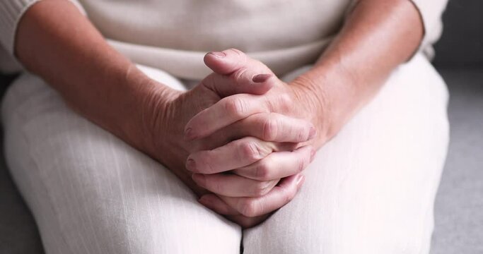 Close up middle aged mature woman clasped hands together, feeling nervous indoors, waiting for health test results. Old retired lady suffering from depression or loneliness, solitude anxiety concept.