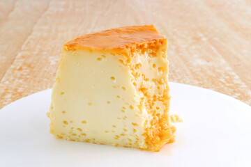 Fatia de pudim de leite condensado com calda de caramelo, tradicional sobremesa brasileira, fotografada isolada em prato branco