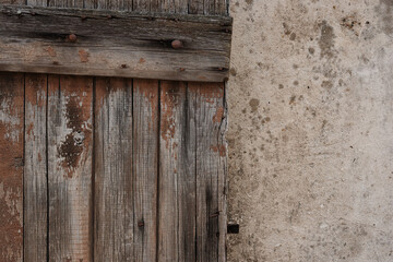 The muted colors of weathered old wood shutter on a colonial era stone building