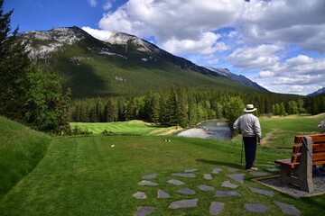 Naklejka premium A man is playing golf in beautiful rocky mountains Banff national park in Alberta, Canada 