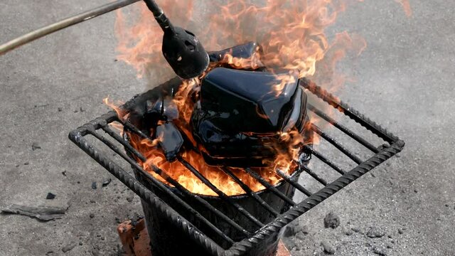 Roof repair. A worker melts the tar with the help of a gas burner and fire for a roof repair