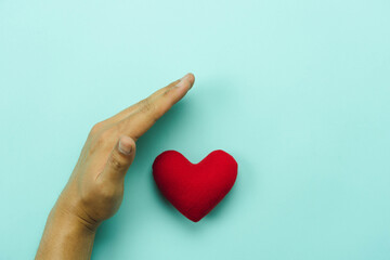 Table top view aerial image of hands protect of red heart on blue paper.Healthcare & medical or valentine background concept. security and insurance, organ donation international day.world health day.