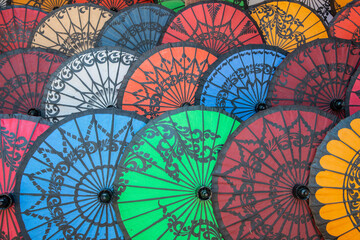 Group of colourful Myanmar parasols sell in souvenir shop.  The Pathein parasol for one is simply enchanting, with its beautiful design containing sort of artistic paintings on them.