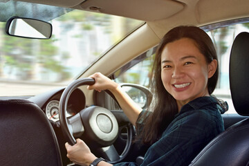 Fototapeta na wymiar Smiling young woman driving a car.