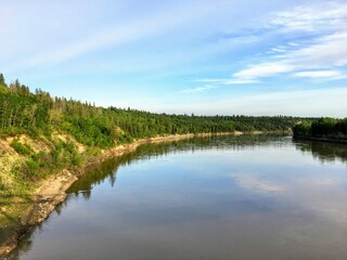 Fototapeta na wymiar A beautiful photo of a gorgeous blue coloured river surrounded by green forest. This is the North Saskatchewan River, in Edmonton, Alberta, Canada.