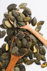 Two wooden spoons filled with pumpkin seeds.