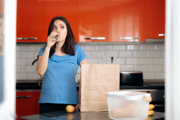 Tired Woman Drinking Water after Shopping for Groceries