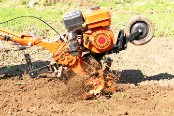 Man Farmer plows the land with a cultivator. Agricultural machinery: cultivator for tillage in the garden,motor cultivator