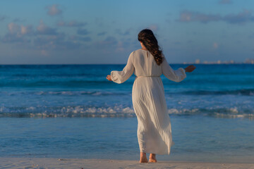 Fototapeta na wymiar A woman on the beach looks at the horizon and walks along the beach.