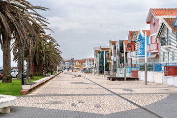 Naklejka premium Street with colorful striped houses, Costa Nova, Aveiro, Portugal. Facades of colorful fisheman houses in Costa Nova, Aveiro, Portugal