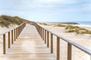 Wooden path at over sand dunes with ocean view. Wooden footbridge of Costa Nova beach in Aveiro, Portugal.