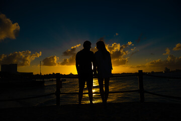 Fototapeta na wymiar Silhouettes of men and women against the backdrop of the setting sun.