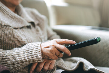 Asian elderly hand holding remote television and watching movie.