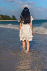 A woman on the beach looks at the horizon and walks along the beach.