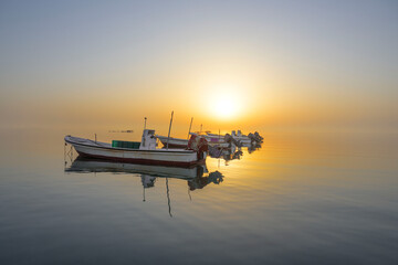 Beautiful image of fisherman boats floating in calm water with colorful sunrise morning reflectiona from sky on water background, Bahrain.