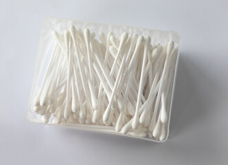 Container of mixed up cotton ear buds on a white background