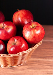 Fresh red apples from left side on brown woven basket