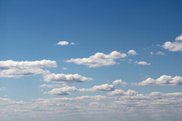 White fluffy clouds on a background of blue sky in summer. The concept of weather and climate.