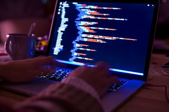 Hacker or software back end developer programming code script late at night hours. HTML, CSS or java script on a laptop computer screen.