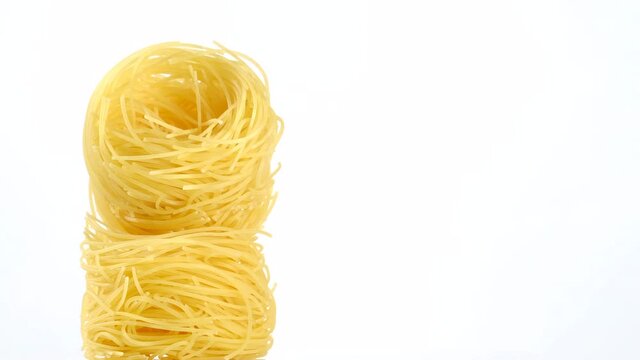 raw pasta capellini rotating isolated on white background. central composition. place for text